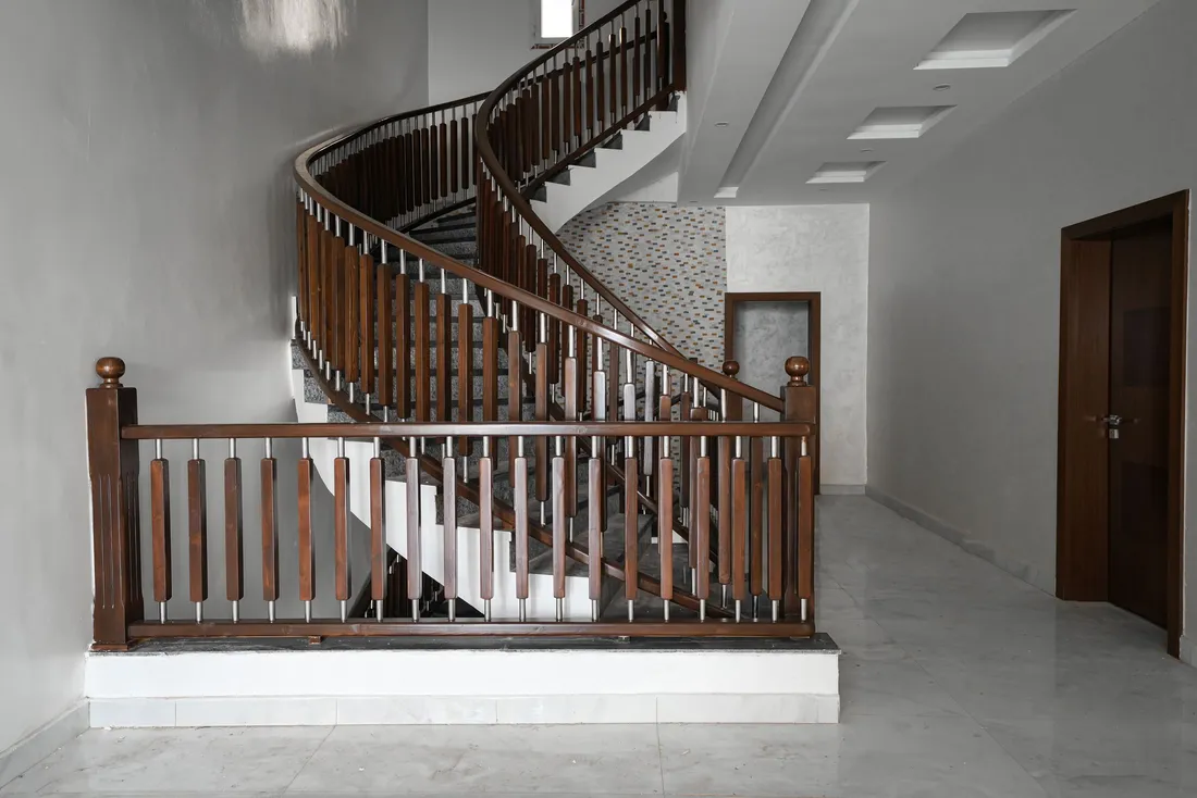 Escalier tournant en bois à balustres, vu depuis le hall