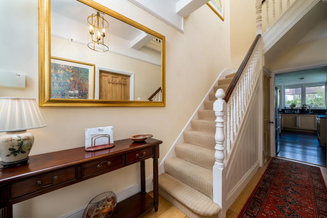 Escalier droit recouvert de moquette, rampe blanche, dans une entrée