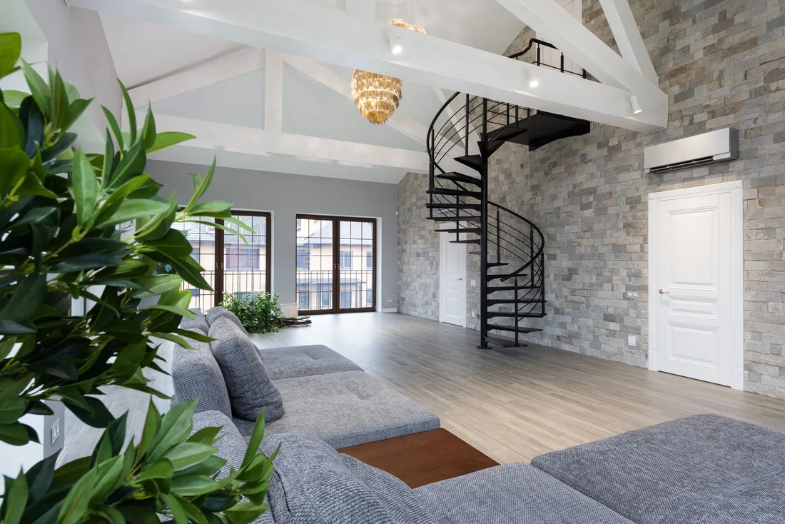 Escalier hélicoïdal métallique dans un séjour à mur de pierre
