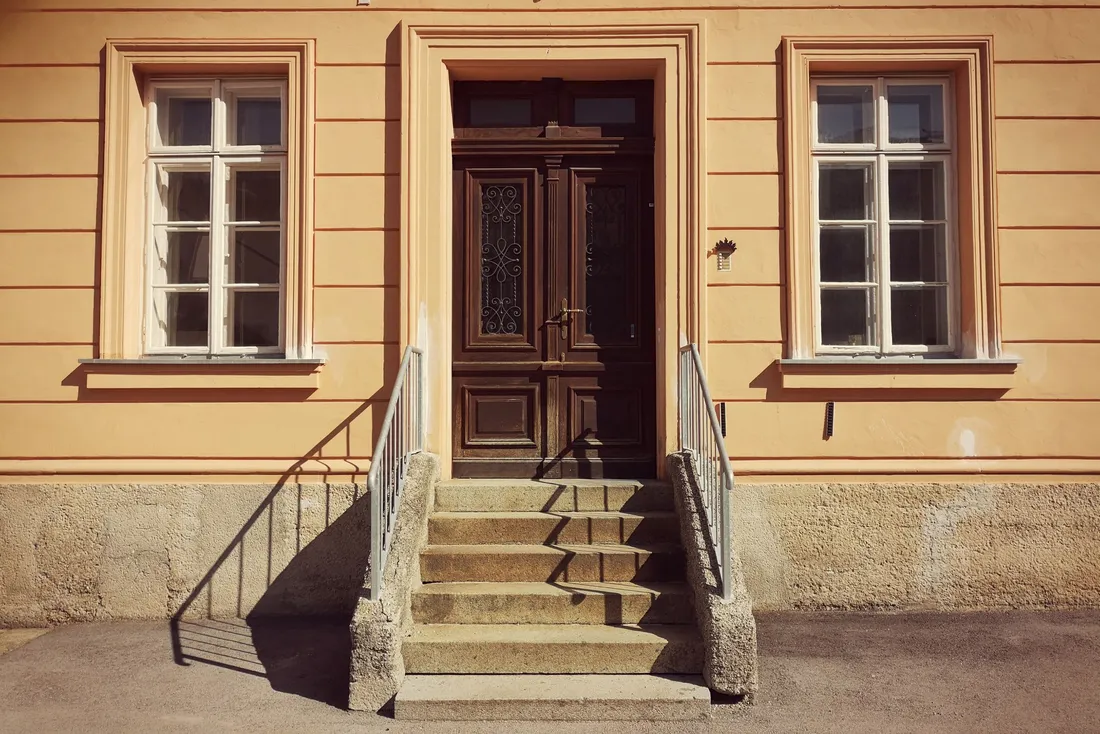 Perron de quelques marches avec rampe métallique devant une maison de ville