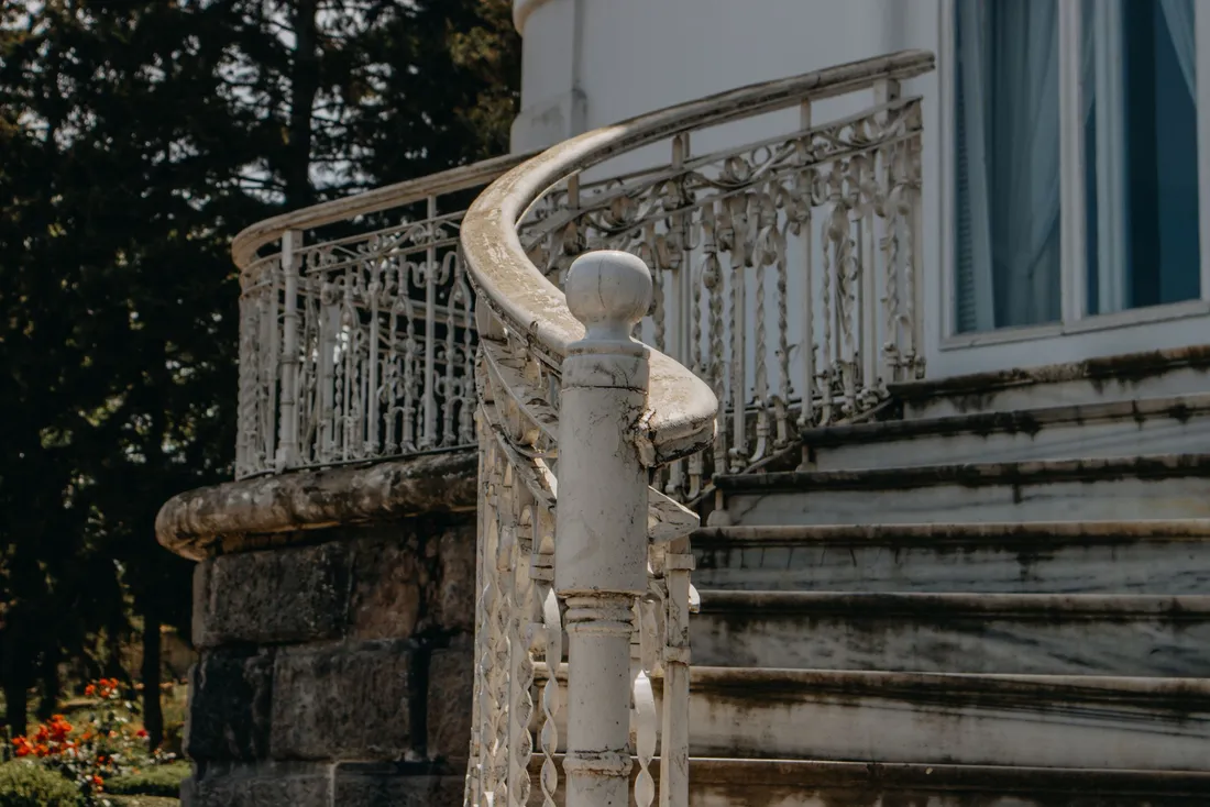 Escalier extérieur en pierre avec une rampe ouvragée en courbe