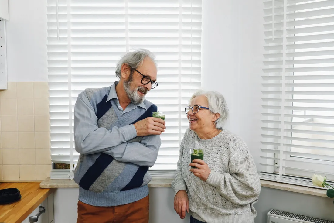 Couple de seniors souriant dans la cuisine de leur maison