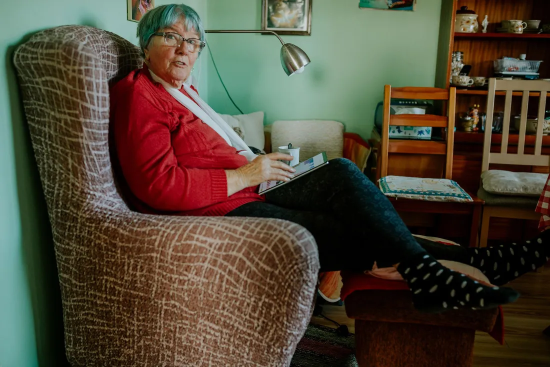 Femme âgée installée dans un fauteuil de son salon